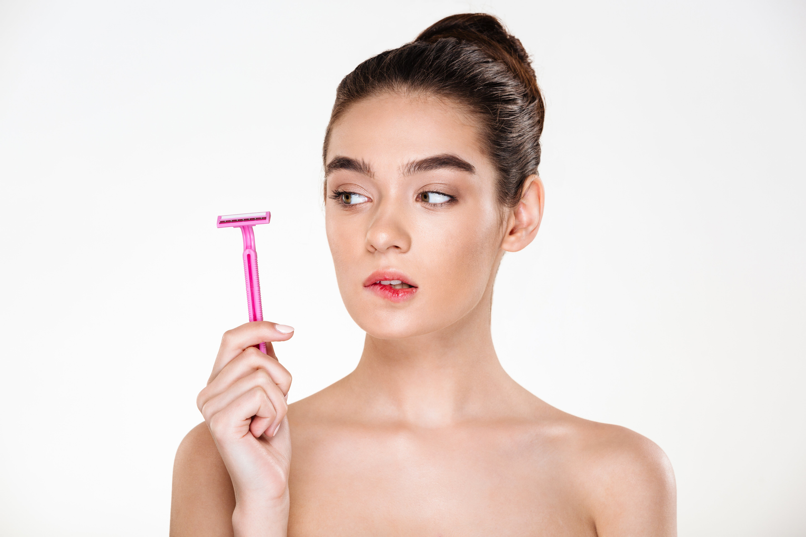 Mulher segurando uma lâmina limpa perto do rosto antes de iniciar a depilação facial